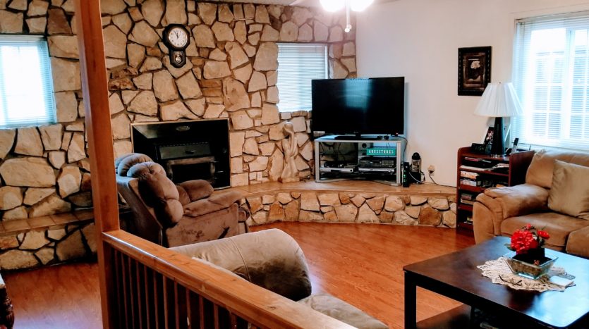 A living room with a couch, chair and television.