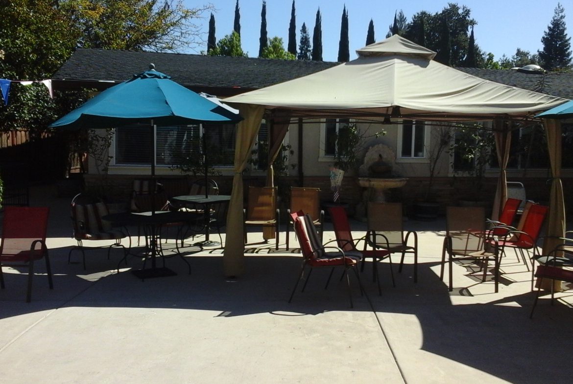 A patio with tables and chairs under an umbrella.