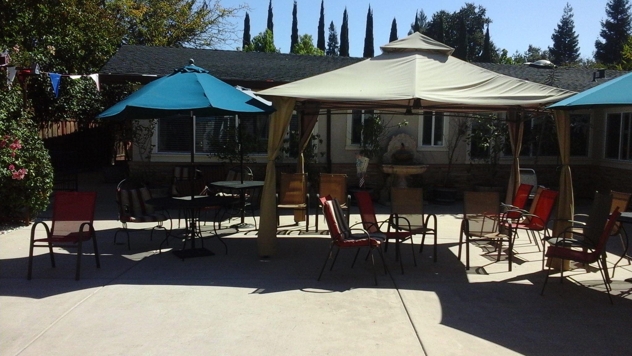 A patio with tables and chairs under an umbrella.