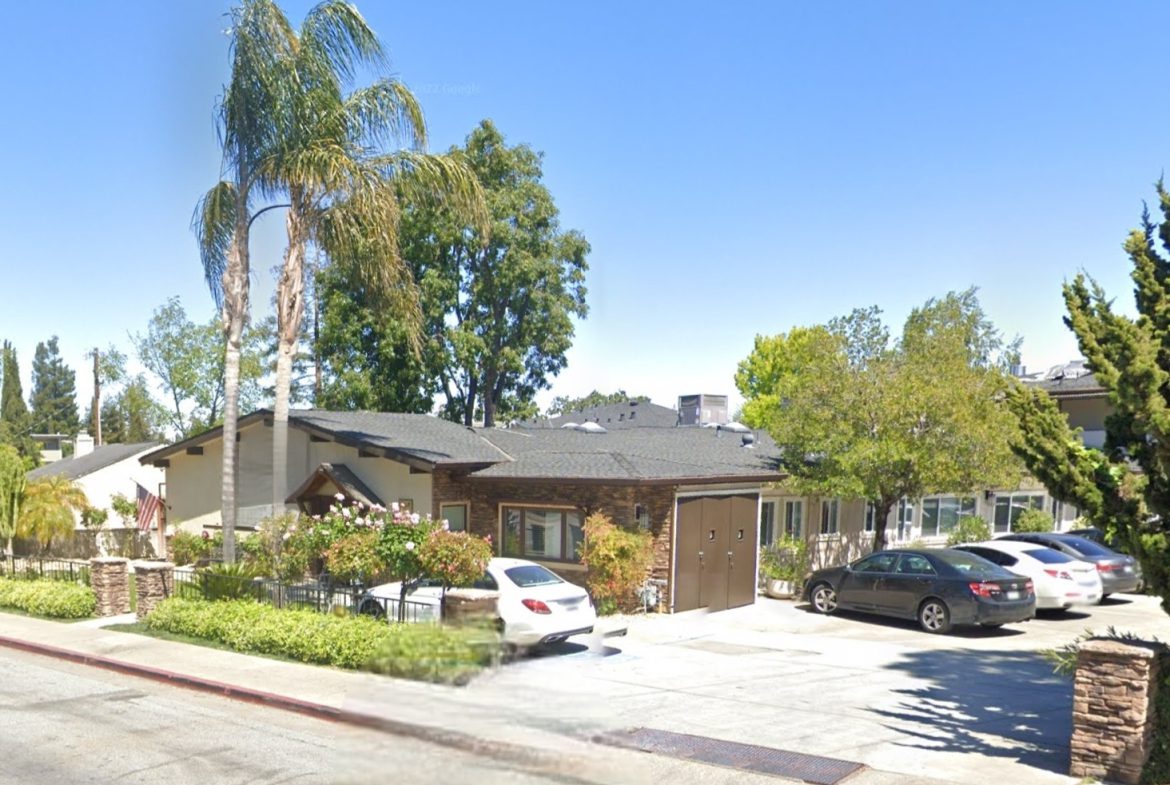 A street view of a house with cars parked in front.