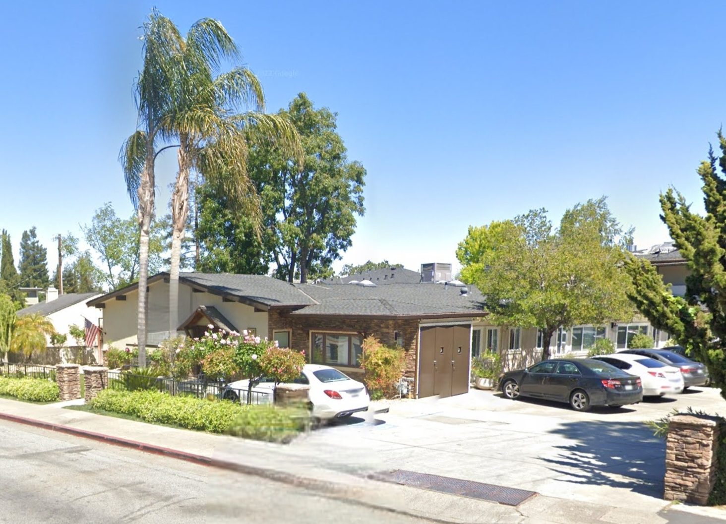 A street view of a house with cars parked in front.