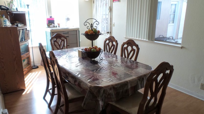 A dining room table with six chairs and a bowl of fruit.
