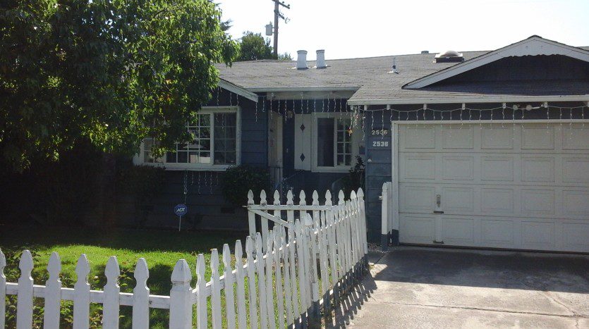 A house with a white fence and a driveway.