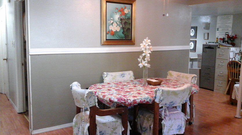 A dining room table with four chairs and a vase of flowers.