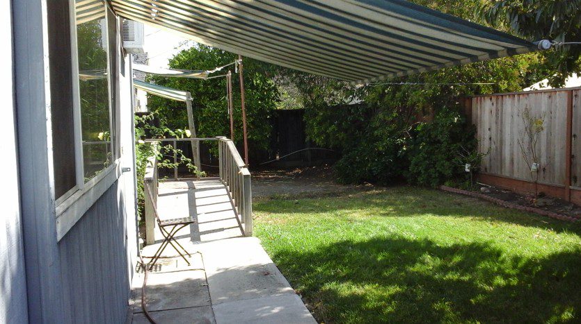 A patio with a lawn and steps leading to the back yard.