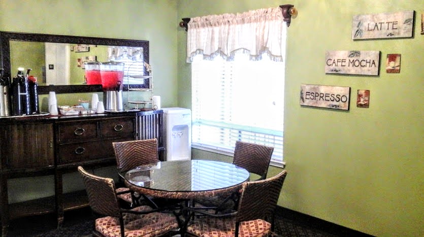 A dining room table with four chairs and a refrigerator.