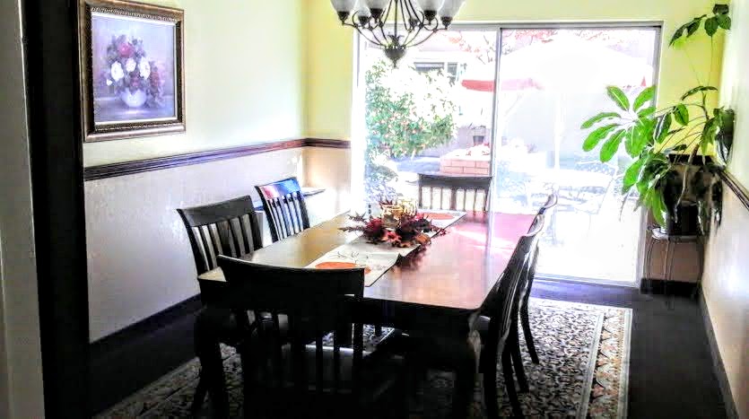 A dining room table with six chairs and a chandelier.
