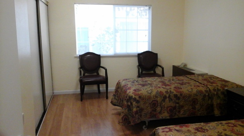 A bedroom with two chairs and a bed