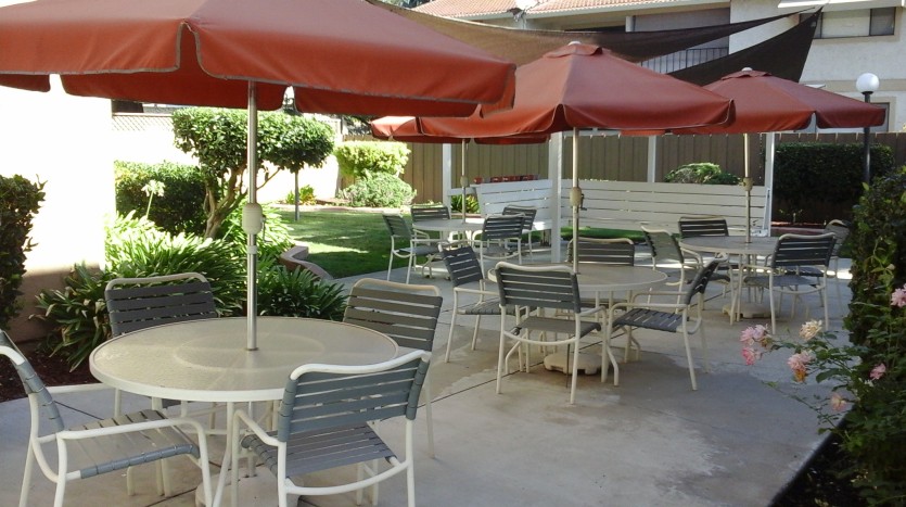 A patio with tables and chairs under umbrellas.