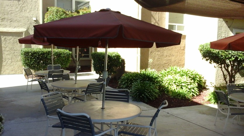 A patio with tables and chairs under an umbrella.