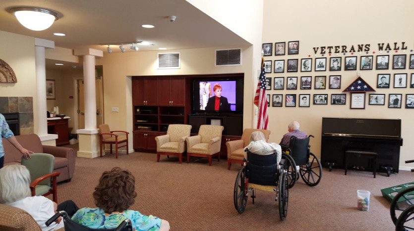 A group of people sitting in chairs watching television.