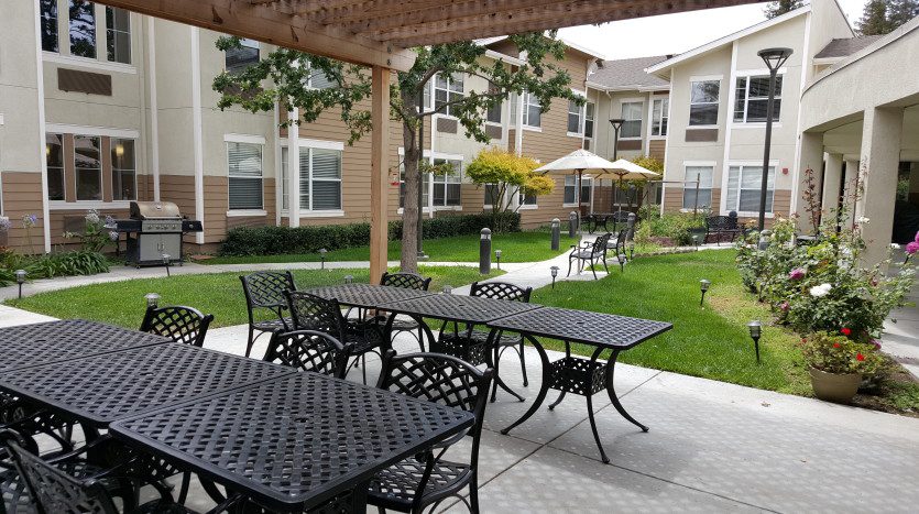 A patio with tables and chairs outside of an apartment complex.