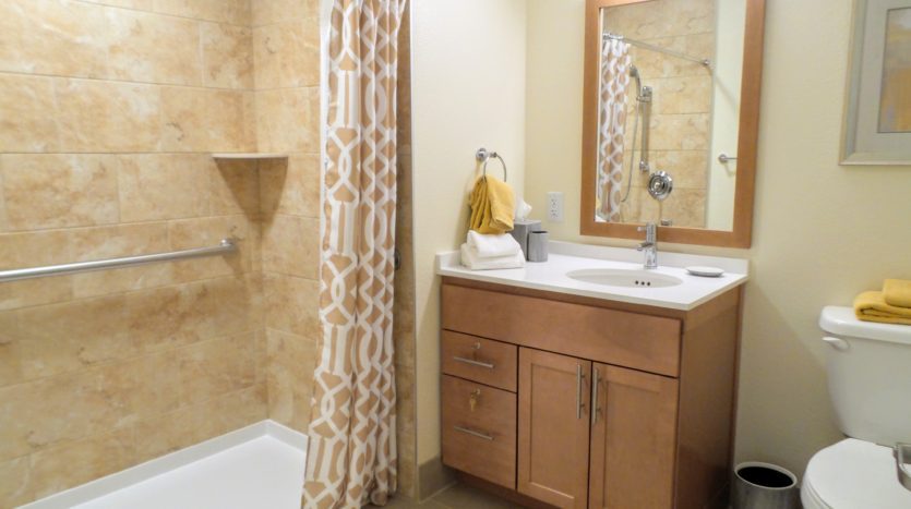 A bathroom with a sink, mirror and shower.