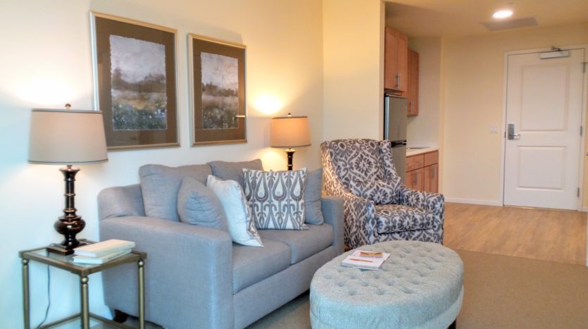 A living room with a couch, chair and ottoman.