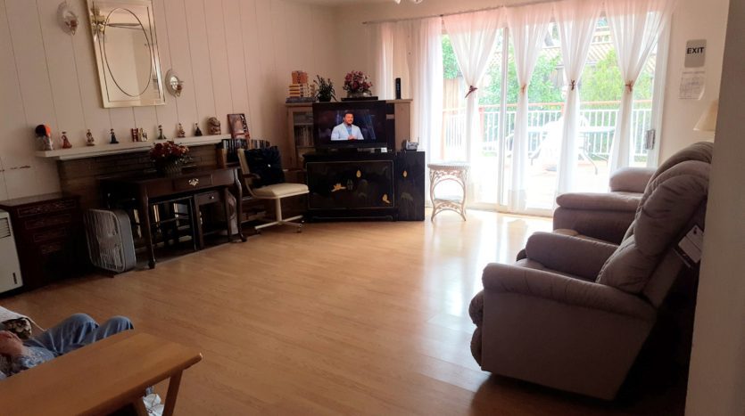 A living room with hardwood floors and a television.