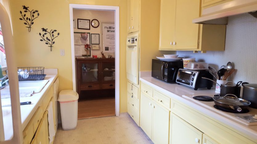 A kitchen with yellow cabinets and white walls.