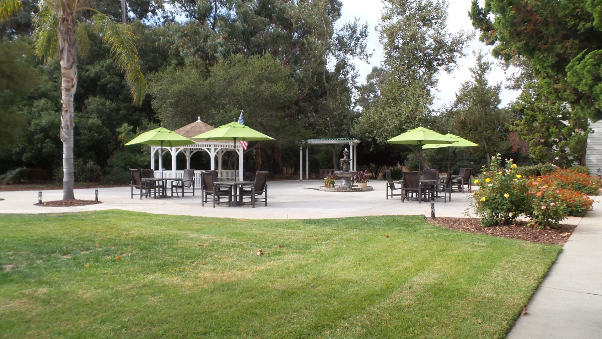 A large lawn with tables and chairs, umbrellas.