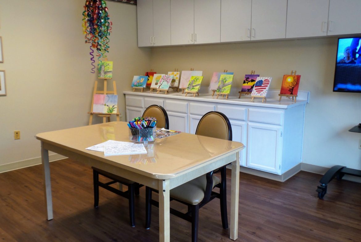 A table with chairs and some paintings on the wall