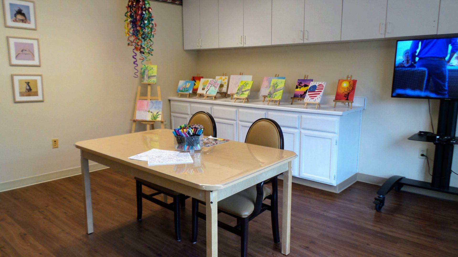 A table with chairs and some paintings on the wall