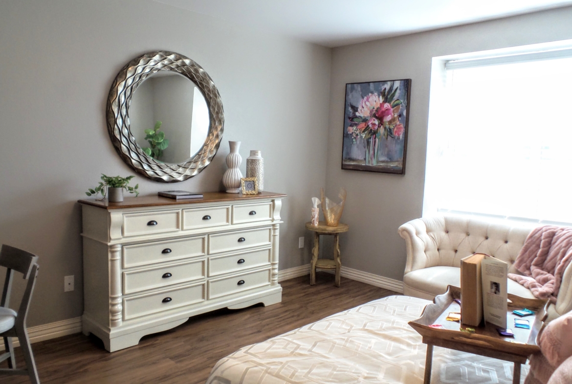 A bedroom with a dresser and chair in it