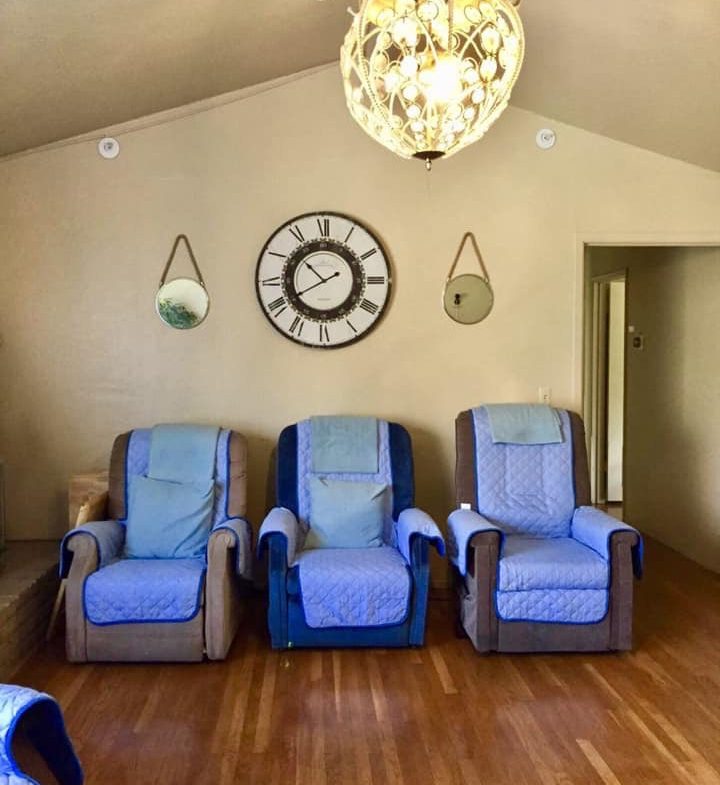 Three blue chairs in a room with a clock on the wall.