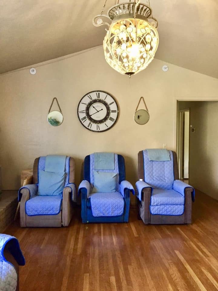 Three blue chairs in a room with a clock on the wall.