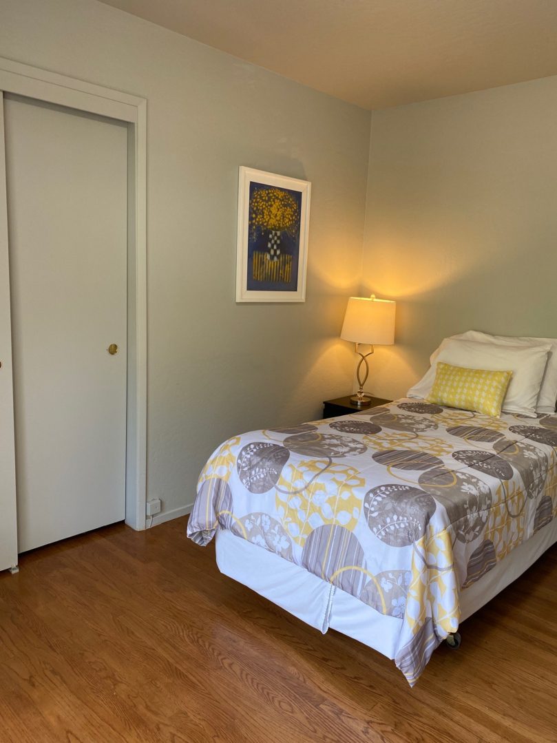 A bedroom with a bed, nightstand and lamp.