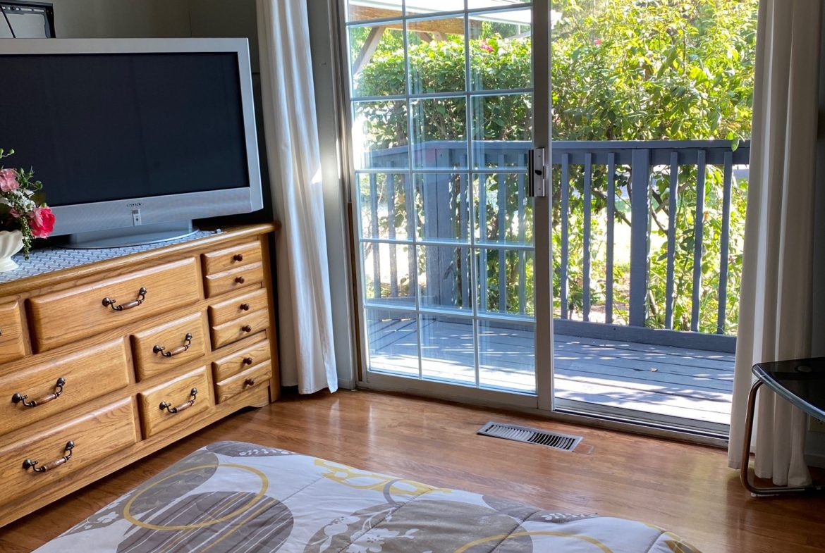 A bedroom with a television and sliding glass doors.