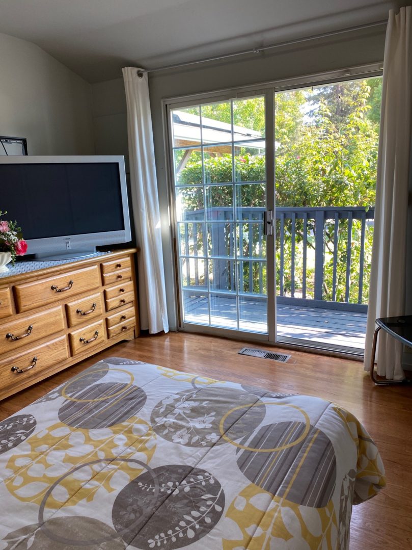 A bedroom with a television and sliding glass doors.