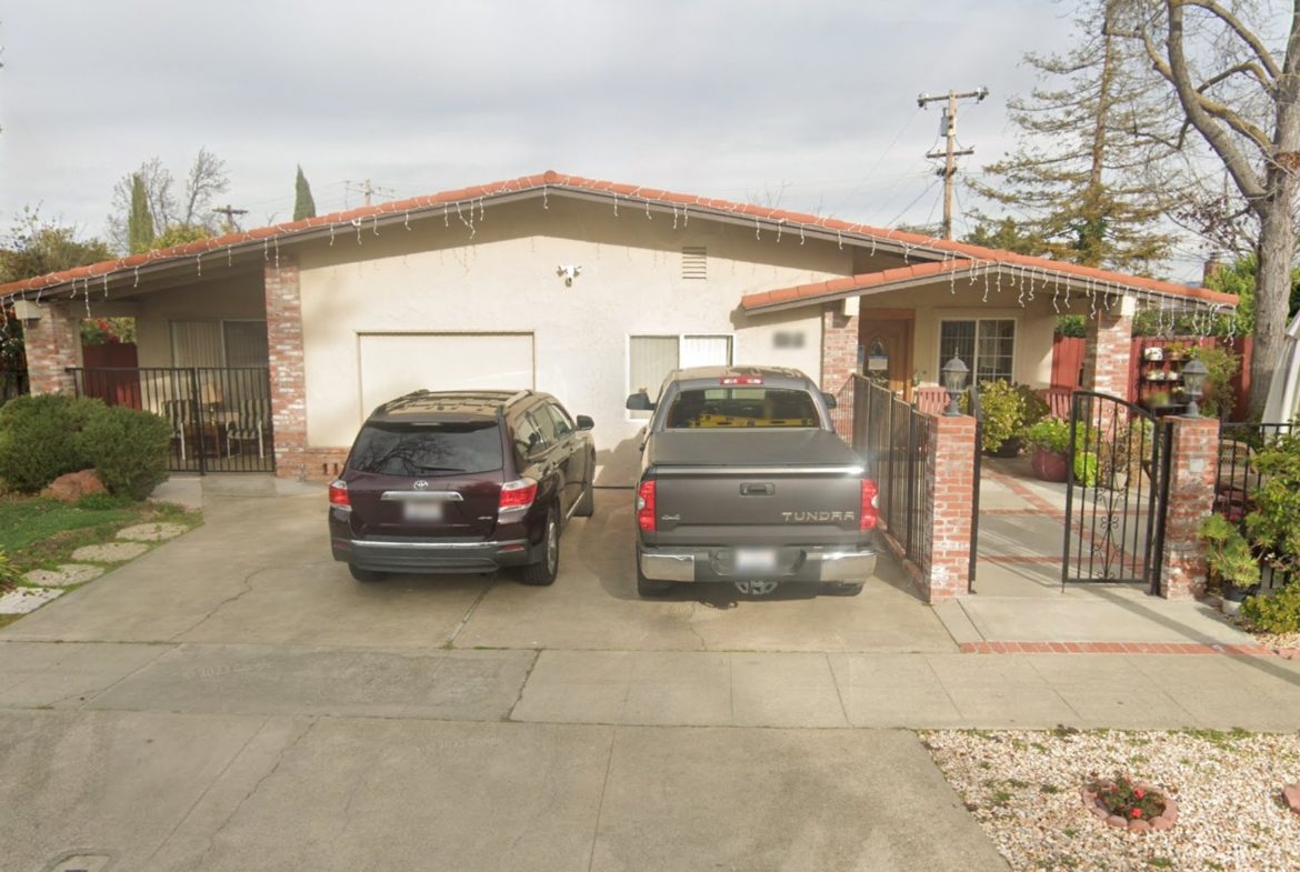 Two cars parked in a driveway next to a house.