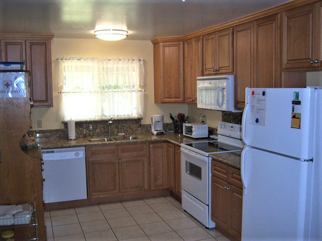 A kitchen with brown cabinets and white appliances.