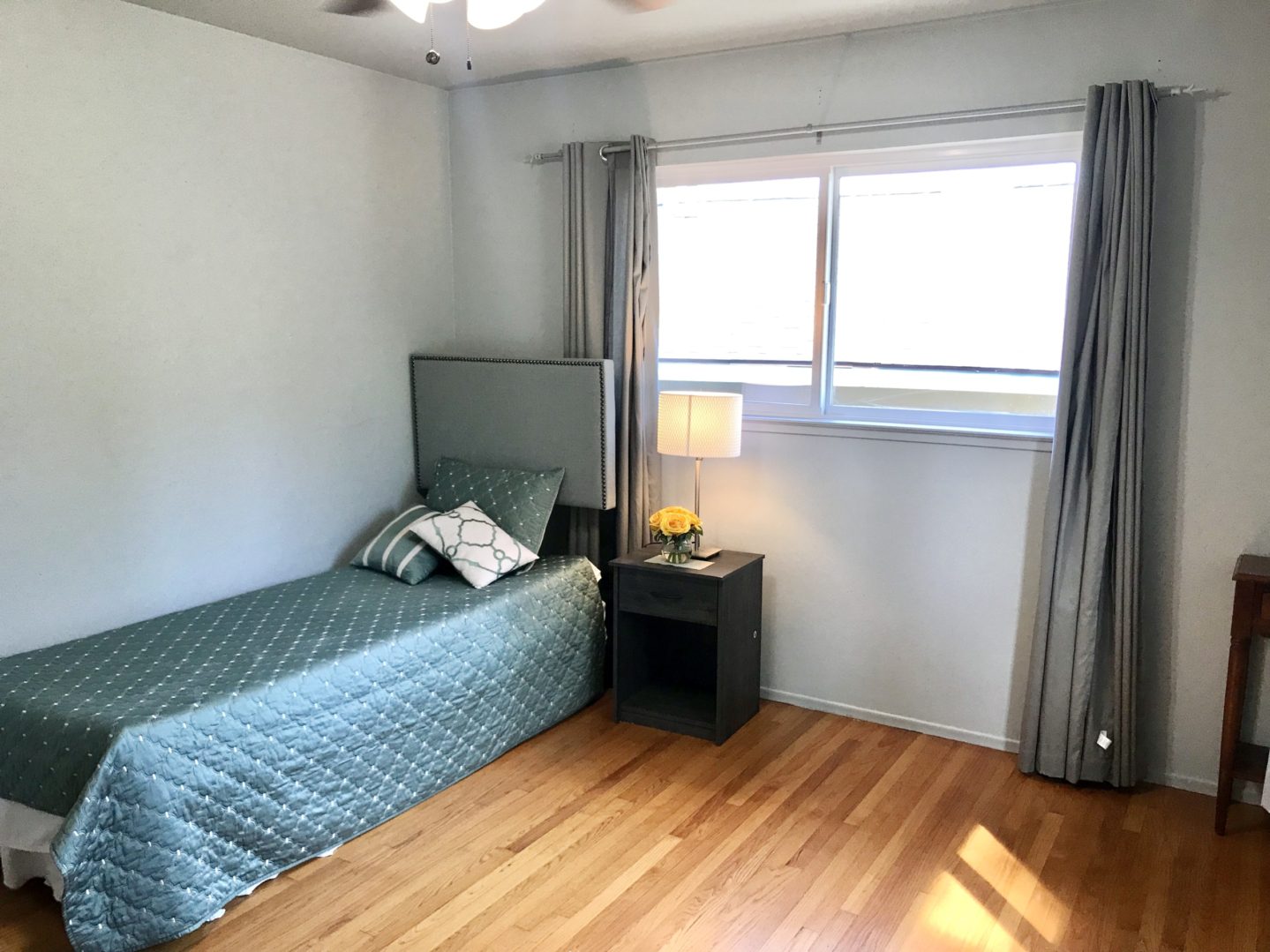 A bedroom with a bed, nightstand and window.