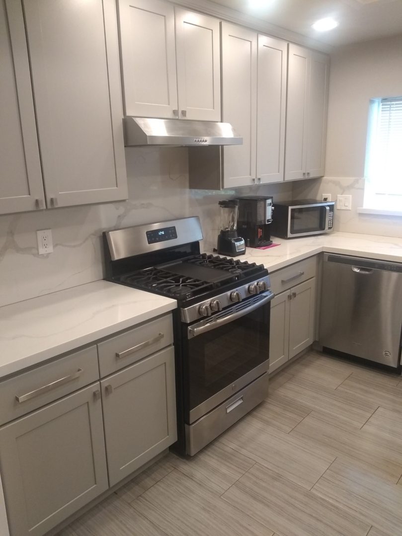 A kitchen with grey cabinets and white counters.