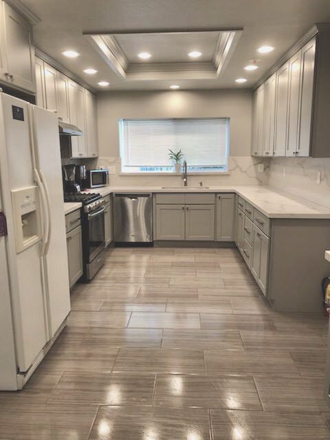 A kitchen with white cabinets and tile floors.