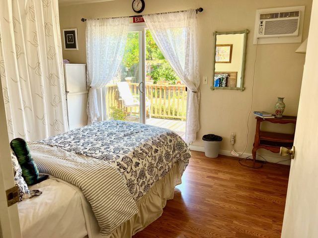 A bedroom with a bed, dresser and window.