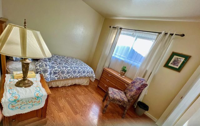 A bedroom with a bed, dresser and chair.