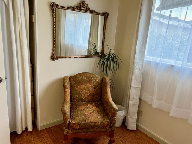 A chair and mirror in the corner of a room.