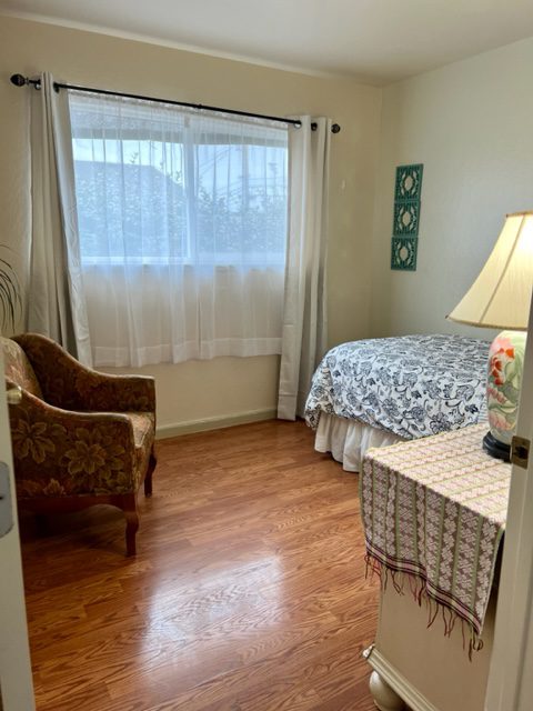 A bedroom with a bed, chair and lamp.