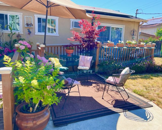 A patio with an umbrella and chairs in the middle of it.