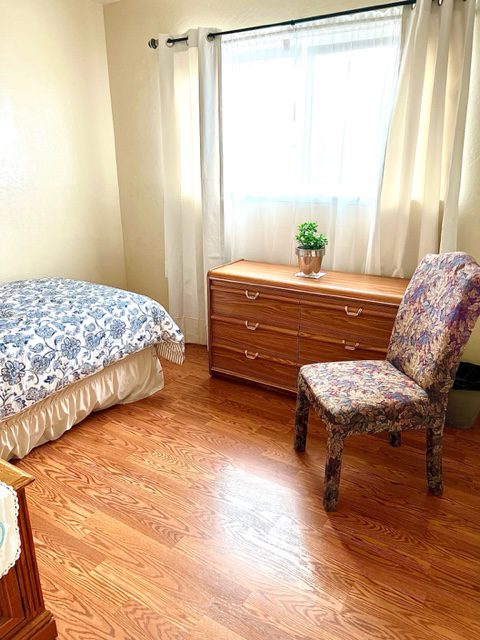 A bedroom with a bed, dresser and chair.