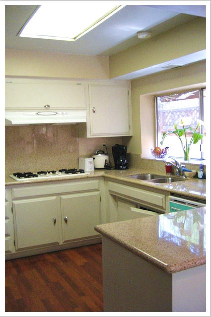 A kitchen with white cabinets and granite counter tops.