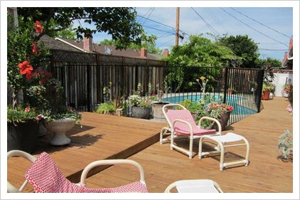 A deck with chairs and a pool in the background.