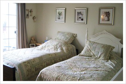 A bedroom with two beds and pictures on the wall.