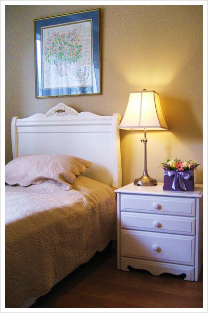 A bedroom with a bed, nightstand and lamp.