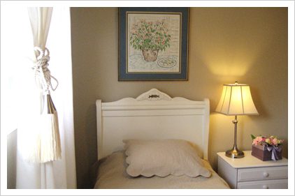 A bed room with a white headboard and a lamp