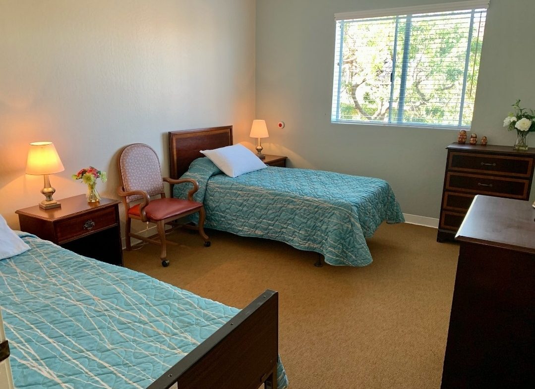 A bedroom with two beds and a desk