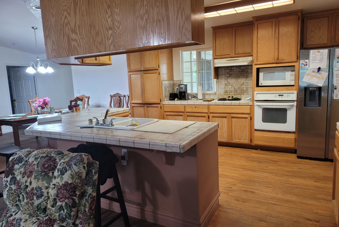 A kitchen with wooden cabinets and wood floors.