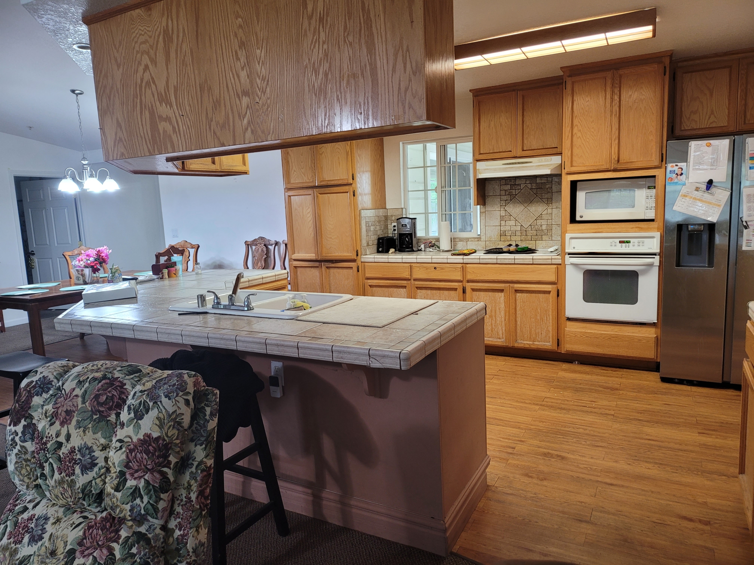 A kitchen with wooden cabinets and wood floors.