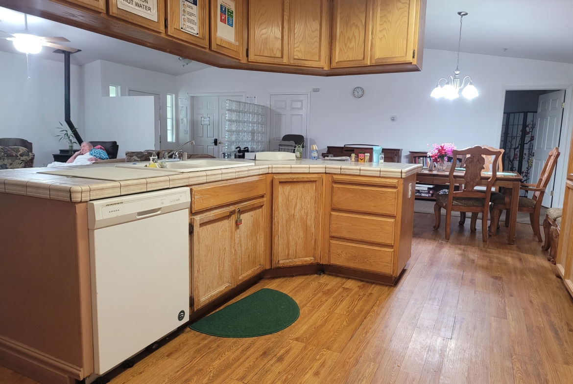 A kitchen with wooden cabinets and hard wood floors.