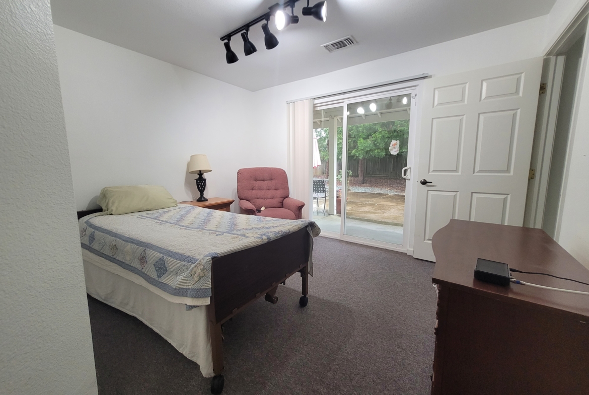 A bedroom with a bed, desk and chair.